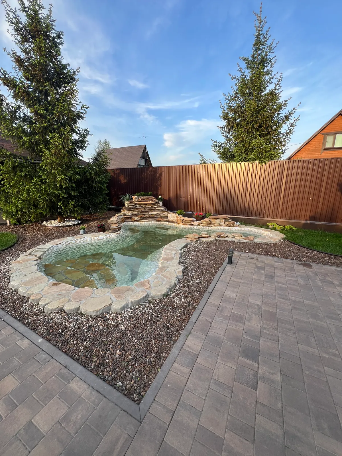 Gartenteich mit Steinrand und Wasserfall im heimischen Garten
